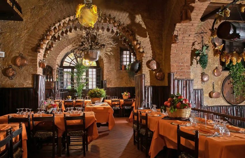 Dining room with brick arches and orange tablecloths at Taverna dello Spuntino