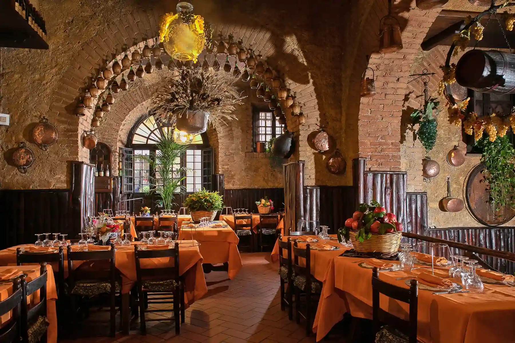 Dining room with brick arches and orange tablecloths at Taverna dello Spuntino