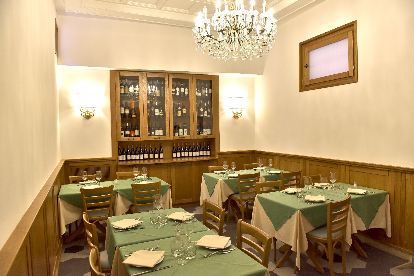 Dining tables beneath a chandelier at Hostaria da Pietro